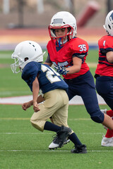 Young athletic boy playing in a youth tackle football game