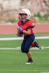 Fototapeta na wymiar Young athletic boy playing in a youth tackle football game