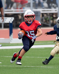 Young athletic boy playing in a youth tackle football game