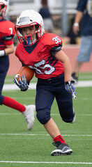 Young athletic boy playing in a youth tackle football game