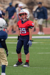 Young athletic boy playing in a youth tackle football game