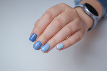 Well-groomed female hand on a white background, manicure with blue gel polish.