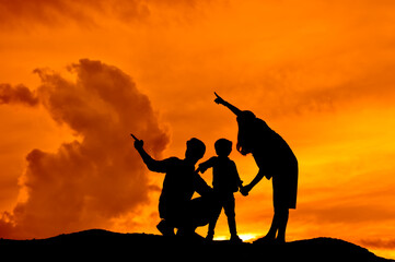 silhouette of happy family father mother and son playing outdoors at sunset.