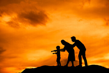 Obraz premium silhouette of happy family father mother and son playing outdoors at sunset.