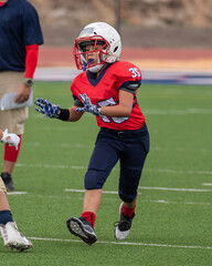 Young athletic boy playing in a youth tackle football game