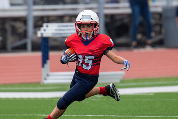 Young athletic boy playing in a youth tackle football game - Powered by Adobe