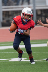 Young athletic boy playing in a youth tackle football game