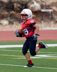 Young athletic boy playing in a youth tackle football game