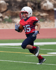 Young athletic boy playing in a youth tackle football game