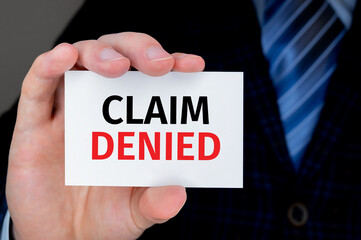 Businessman holding a card with text CLAIM DENIED. Business and financial concept.
