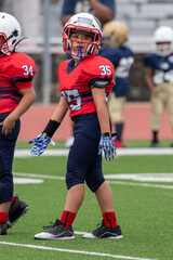 Young athletic boy playing in a youth tackle football game