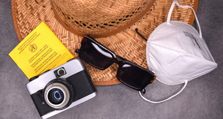 Reisegepäck 2021: Sonnenhut, Maske, Impfausweis,   Fotoapparat und Sonnenbrille