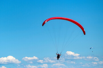 Panoramic photo of two people paraglider in blue sky