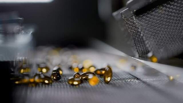 Gelatin capsules in the production of vitamins and medicines. Supplements are made on an automatic machine or medical conveyor equipment. Pharmacological plant of amber-colored drugs. Slow motion