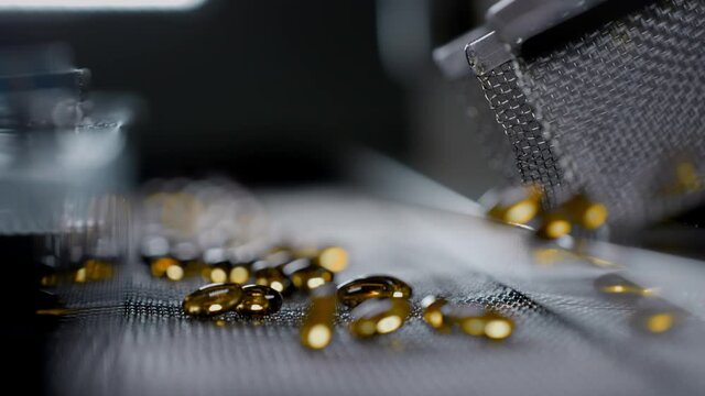 Fish oil gelatin capsules in the production of vitamins and medicines. Supplements are made on an automatic machine or medical conveyor equipment. Pharmacological drug plant. Slow motion