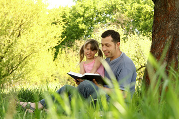 young father with a small daughter reading the Bible
