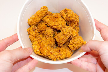 Deep fried spicy chicken wings in a crispy breading in a basket in hands, chicken fast food isolated on white background