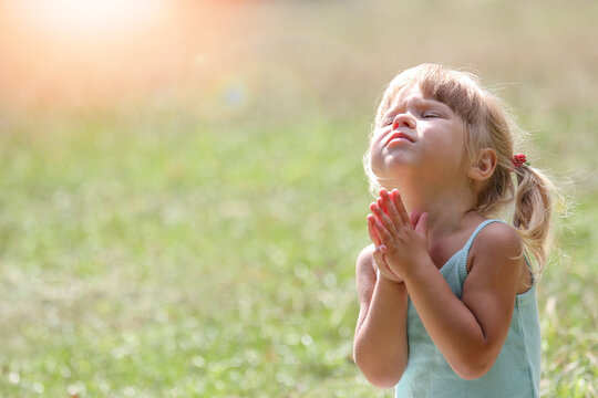 happy clittle girl praying in nature
