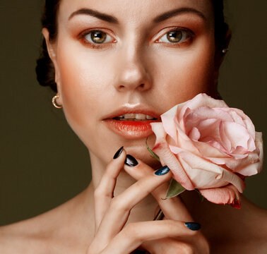beautiful young woman with makeup in gentle colors holds a big pink rose, beauty concept
