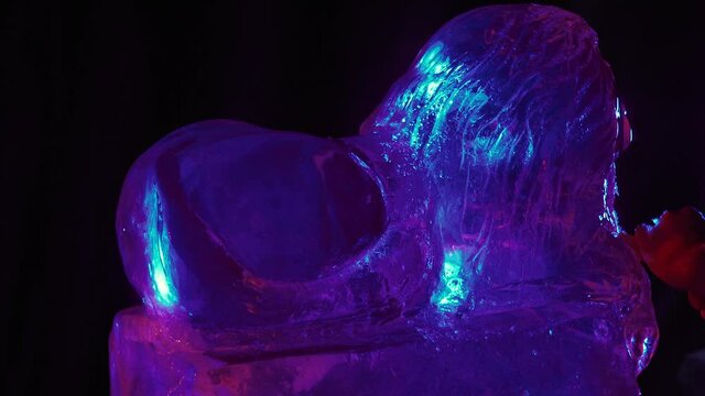 Blue lighting, a man is working with a chisel on an ice sculpture of a lion, 4k