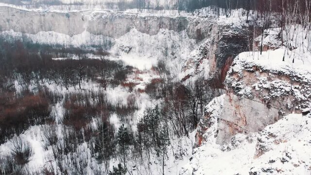 Aerial footage of Kamieniolom Liban. Remains of a limestone quarry WWII labor camp. This has served as a film set for a Holocaust movie. Light Snowfall during the winter season. Grove of trees. 