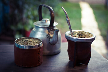 mate tradicional argentino con una pava de acero y un recipiente de yerba mate sobre la mesa,...