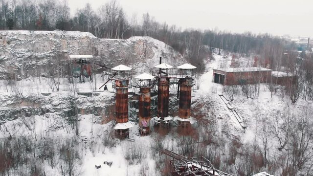 Drone View of Kamieniolom Liban - A historic site where prisoners were kept during Second World War. Old machines and piping equipment. Light snow-fall. Grove of trees in the foreground. 
