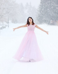 Fototapeta na wymiar Teen girl in pink formal dress on snowy day outdoors