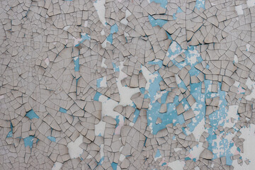 Peeling paint on the wall. Old concrete wall with cracked flaking paint. Weathered rough painted surface with patterns of cracks and peeling. Grunge texture for background and design. High resolution.