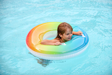 Kids summer swimming. Summertime vacation. Child at aquapark. Funny boy on inflatable rubber circle in pool.