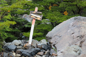 Signboard in nature with trees and rocks.
