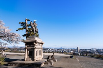 Fototapeta na wymiar 桜と仙台市街を見下ろす伊達政宗像　騎馬像
