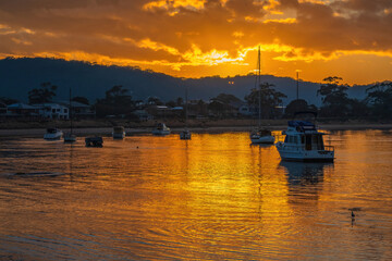 Golden sunrise waterscape with boats and cloud cover