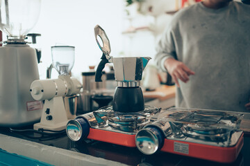 Brewing black moka coffee using moka coffee maker and boiling on stove.