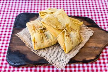 Traditional Andean corn and meat tamales served on a wooden board. Regional food.