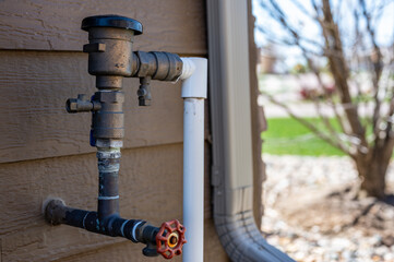 Test cocks, shut off valves, and vacuum breaker to a lawn sprinkler irrigation system on the outside of a residential house - obrazy, fototapety, plakaty