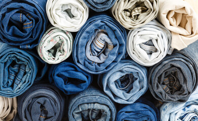 background from stack of different rolled jeans. Roll blue denim jeans arranged in stack. Jeans pyramid. Recycling old blue jeans on wooden table. Denim upcycle. Zero waste - 431089702