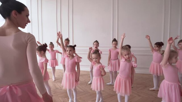 Girls dancers in ballet school learns to dance. Little Ballerinas in training in pink dancing suit. Children's ballet school. School of ballet.