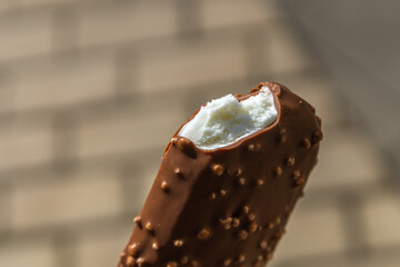 Bitten off white ice cream covered with milk chocolate with nuts