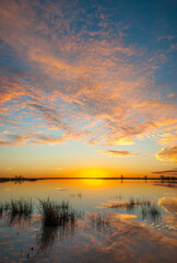 Fototapeta premium Sunrise over Coongie Lakes in the central desert area of Australia with the clouds turning orange