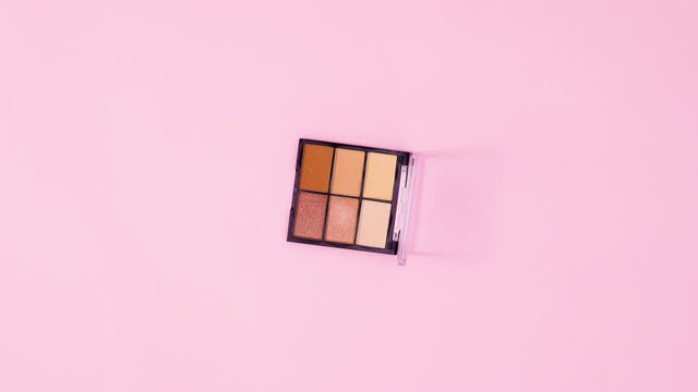 Eye shadow palettes rotating and changing on pastel pink background. Stop motion 