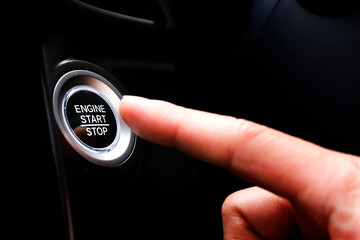 The driver's hand is pressing the car start button. Concept of transportation and technology - obrazy, fototapety, plakaty