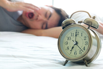 The morning of the new day. Alarm clock in bed The background of the young man sleeping in the bed...