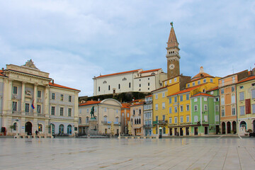 Fototapeta na wymiar The Tartini square of Piran with colorful houses, shops, cafes, a monument and a town hall is empty after the rain.