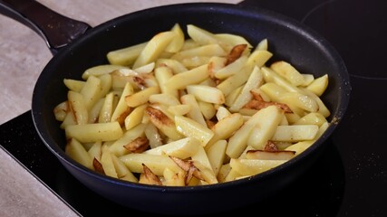 Closeup homemade French fries in frying pan at kitchen stove. Cooking of crispy fried potatoes with curry. Home fries in skillet top view