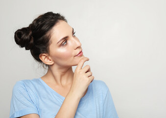 young brunette woman with her fingers to her chin reminiscing and recalling fond memories, close up portrait.