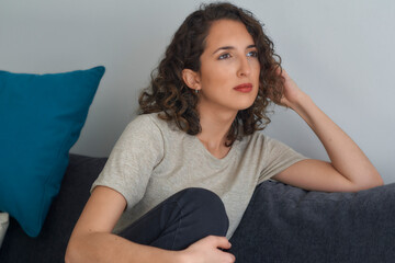 Young woman sitting peacefully in an armchair, thinking and reflecting.