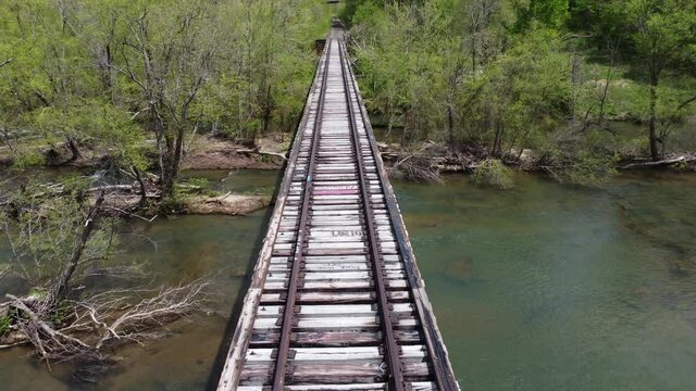 A trestle bridge over a river in a park under the sunlight shot in 4K