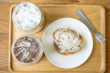 Almond croissant focus on a white plate on a wooden table with two iced coffee mugs on the sides,top view