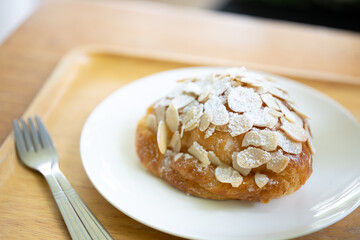 Almond croissant on a white plate on a wooden table